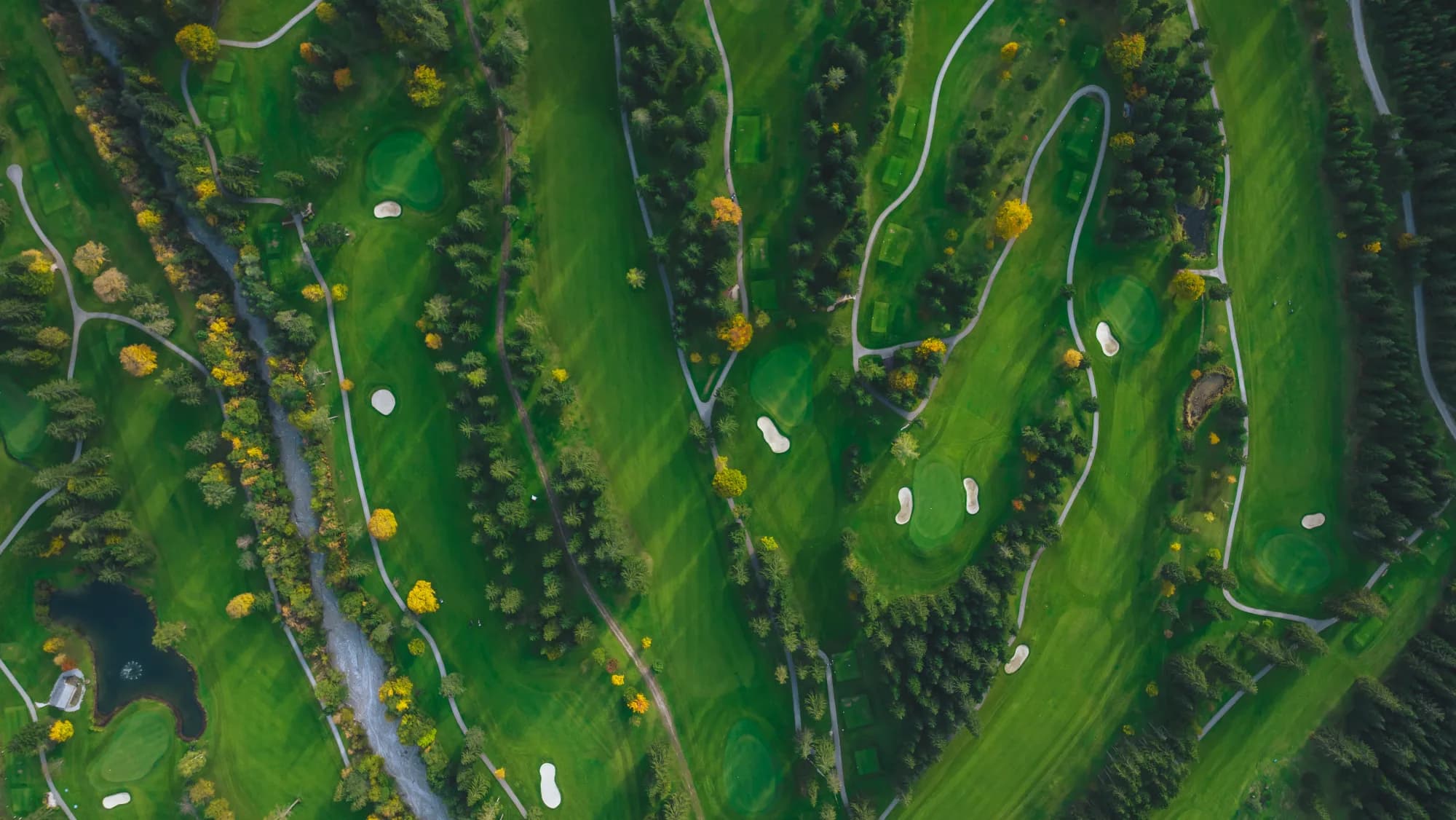 Golfer schlägt aus dem Bunker, dahinter die Gipfel des Rofan