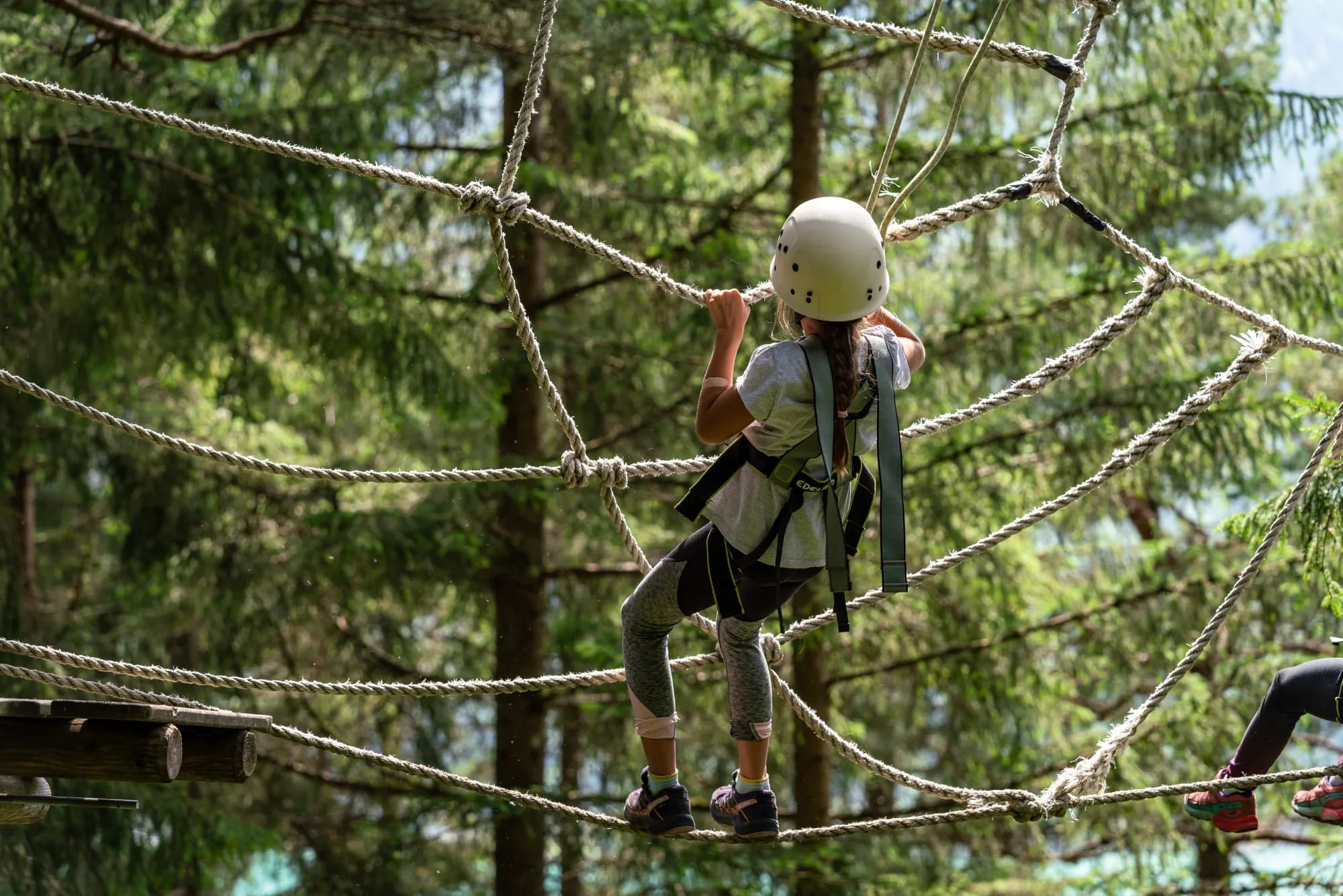 Kind klettert beim Kinderprogramm Achensee, gesichert von einem Guide