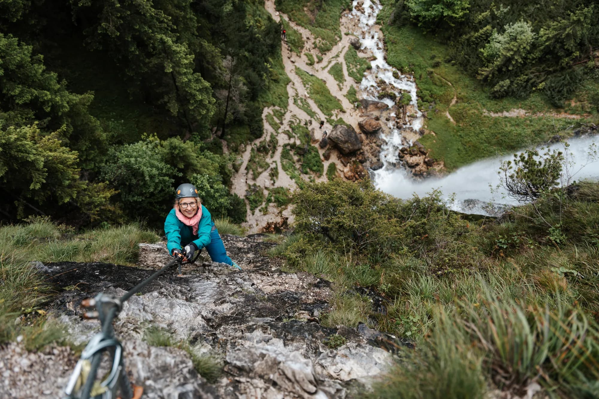 Kletterin am Klettersteig beim Dalfazer Wasserfall, unten der Wildbach im Wald