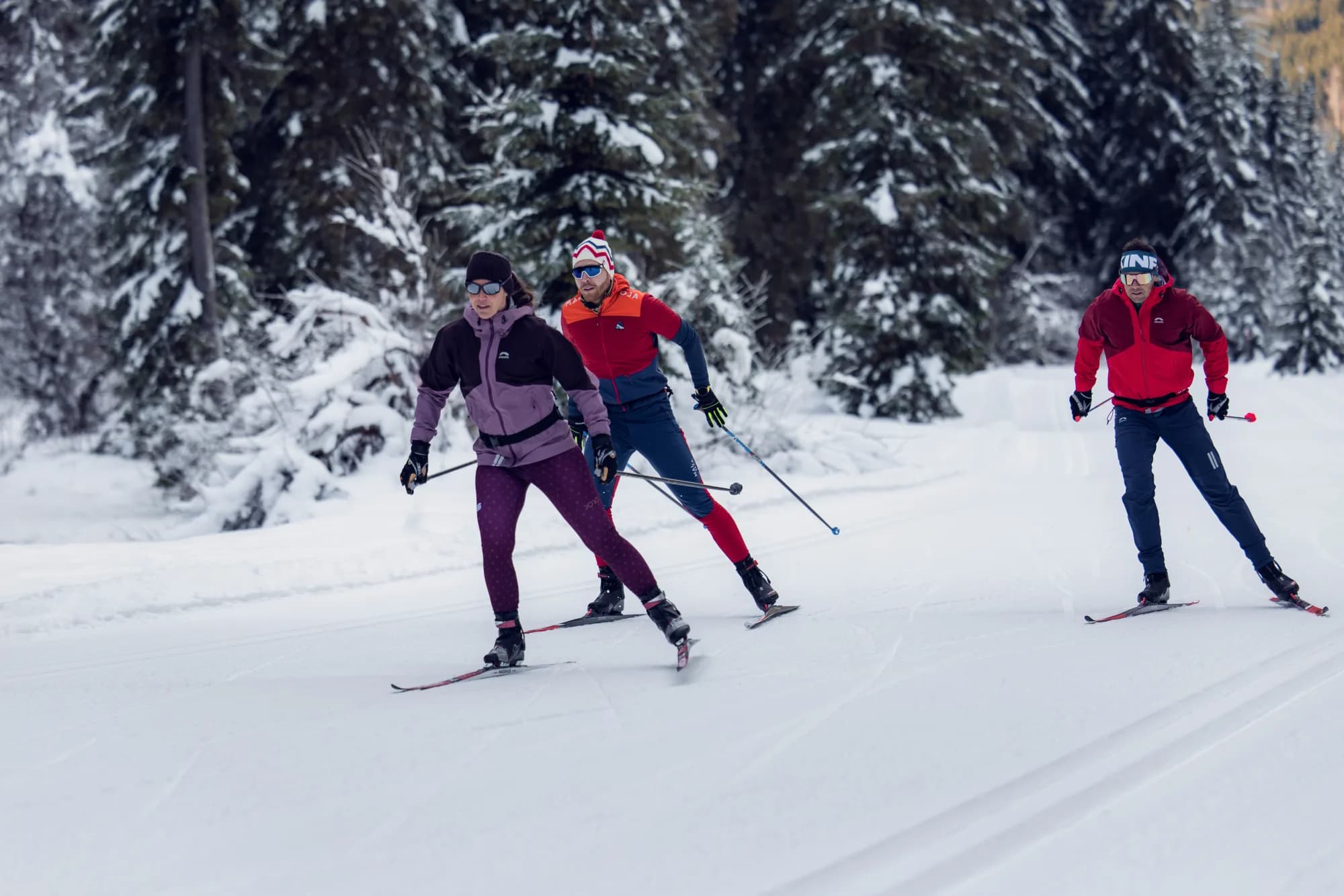 Drei Langläufer skaten durch die schneebedeckte Loipe im Unterautal in Achenkirch