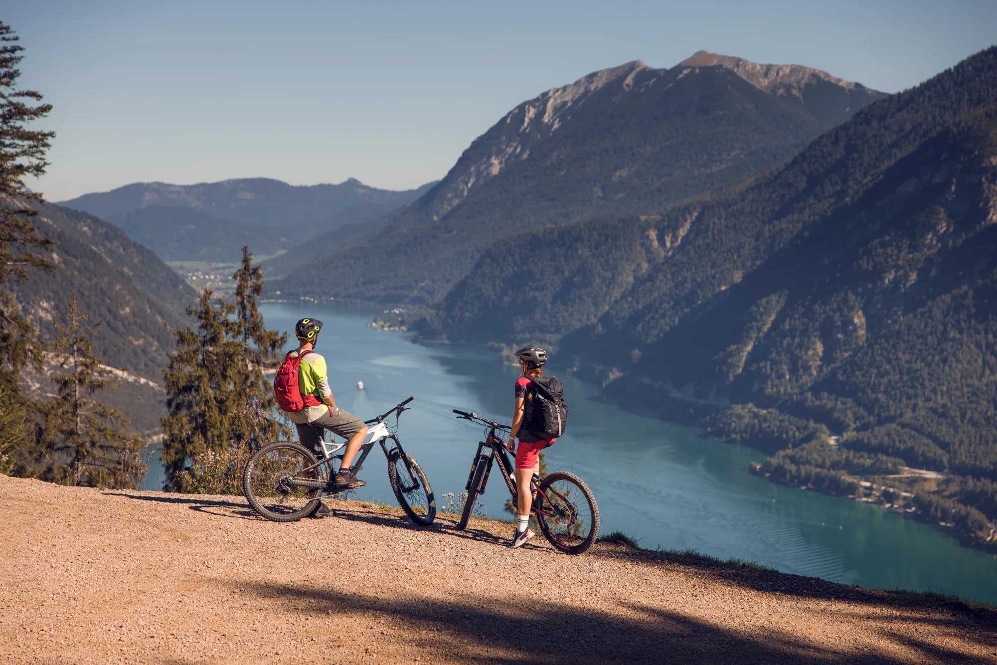 Zwei E-Mountainbiker blicken vom Zwölferkopf auf den fjordartigen Achensee