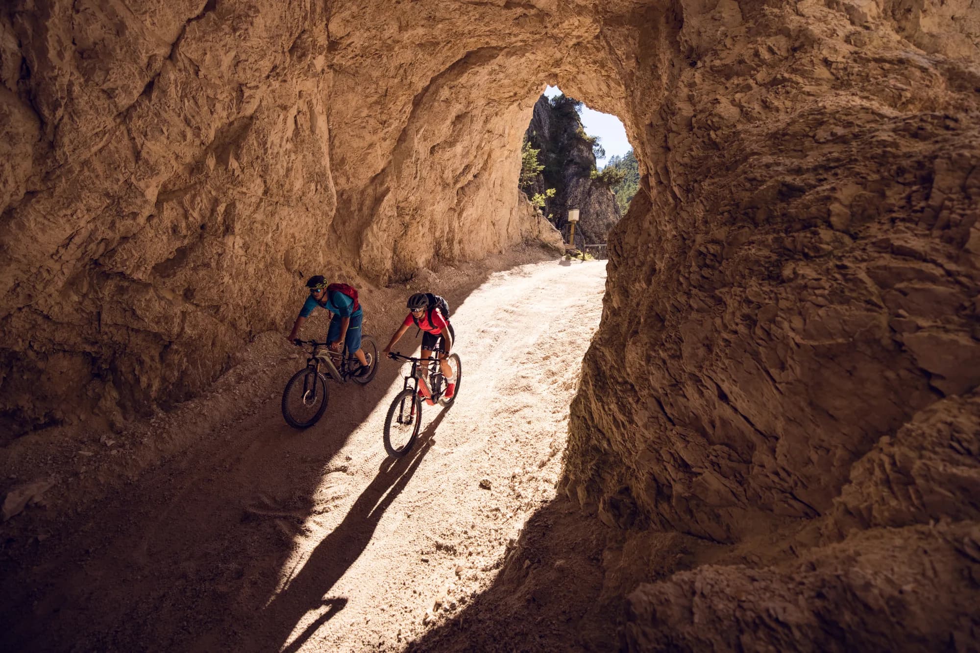 Zwei E-Mountainbiker durchqueren die enge Felsschlucht der Schmalzklause bei Steinberg am Rofan