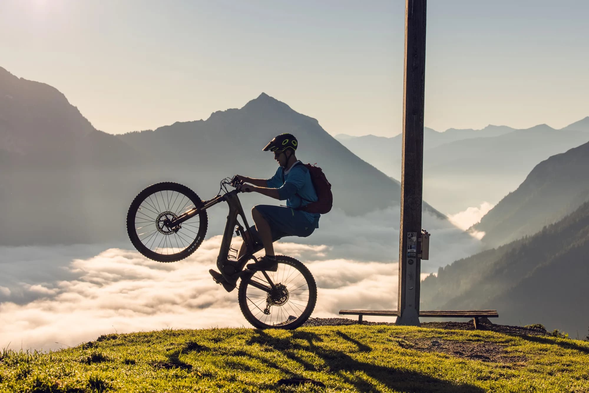 Mountainbiker im Gegenlicht beim Wheelie hoch über dem Nebelmeer am Feilkopf