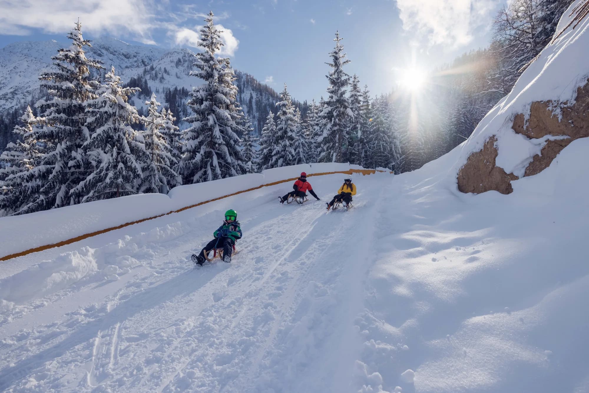 Zwei Rodler sausen nebeneinander die verschneite Rodelbahn am Zwölferkopf hinunter