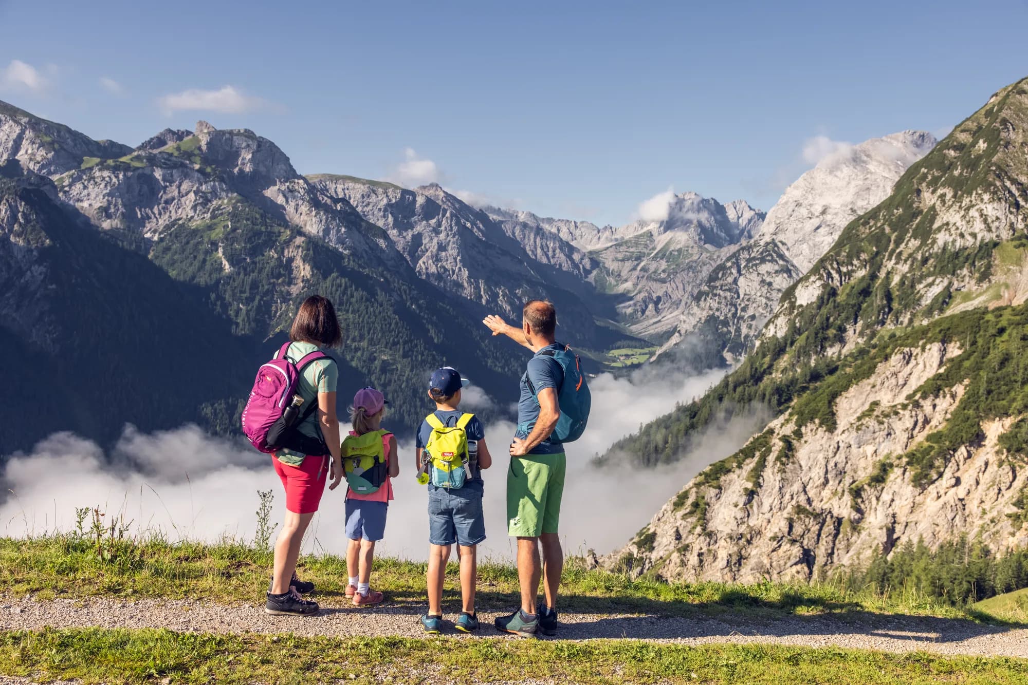 Familie blickt von einem Aussichtspunkt im Naturpark Karwendel über die Nebelwolken ins Tal