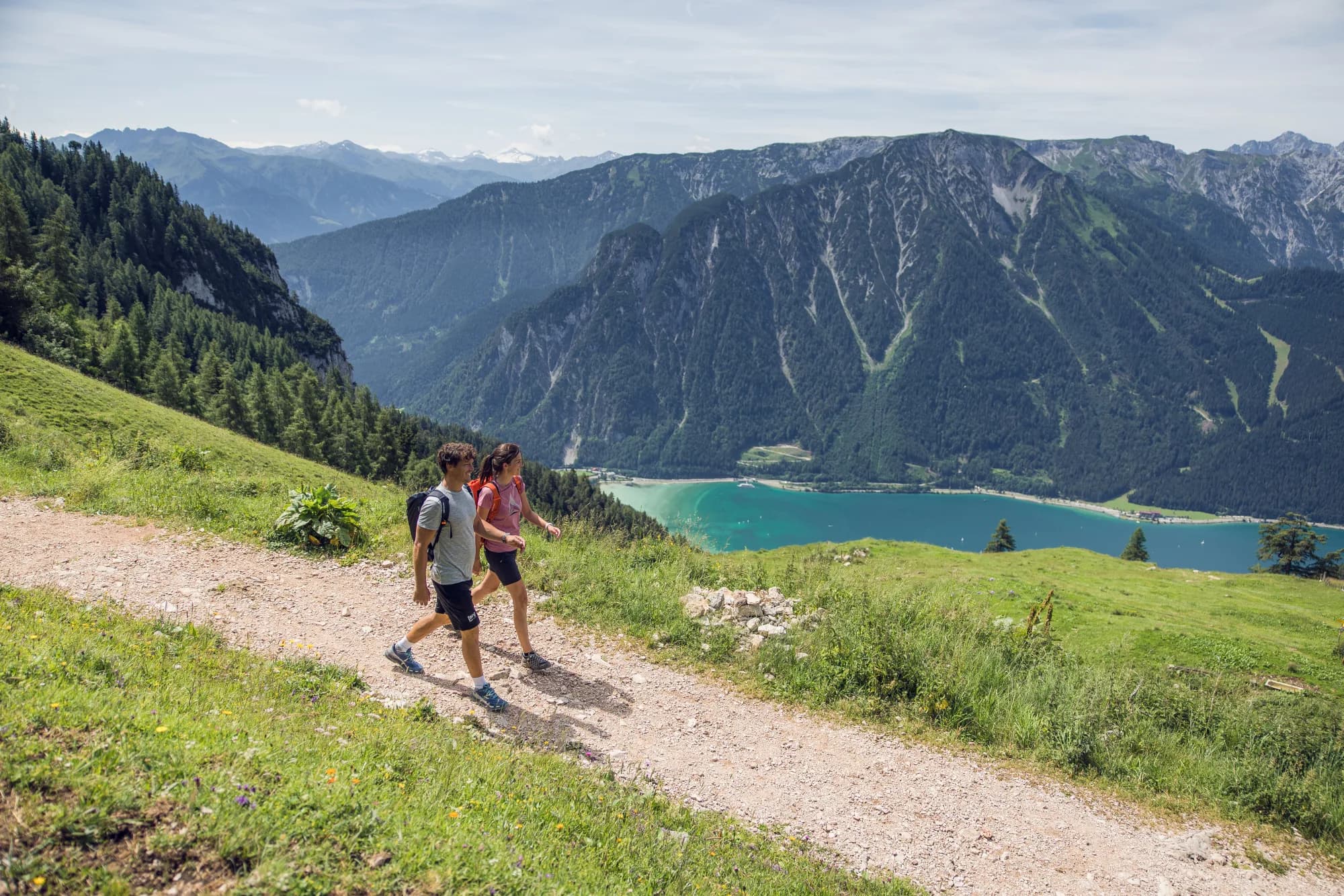 Paar wandert über eine blühende Bergwiese im Rofangebirge