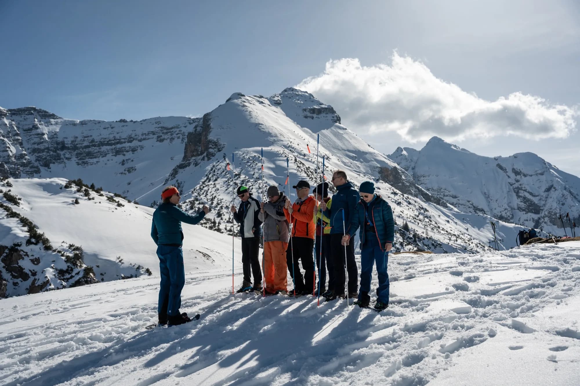 Gruppe übt beim Lawinentraining im Karwendel den Umgang mit Lawinensonden, dahinter verschneite Gipfel