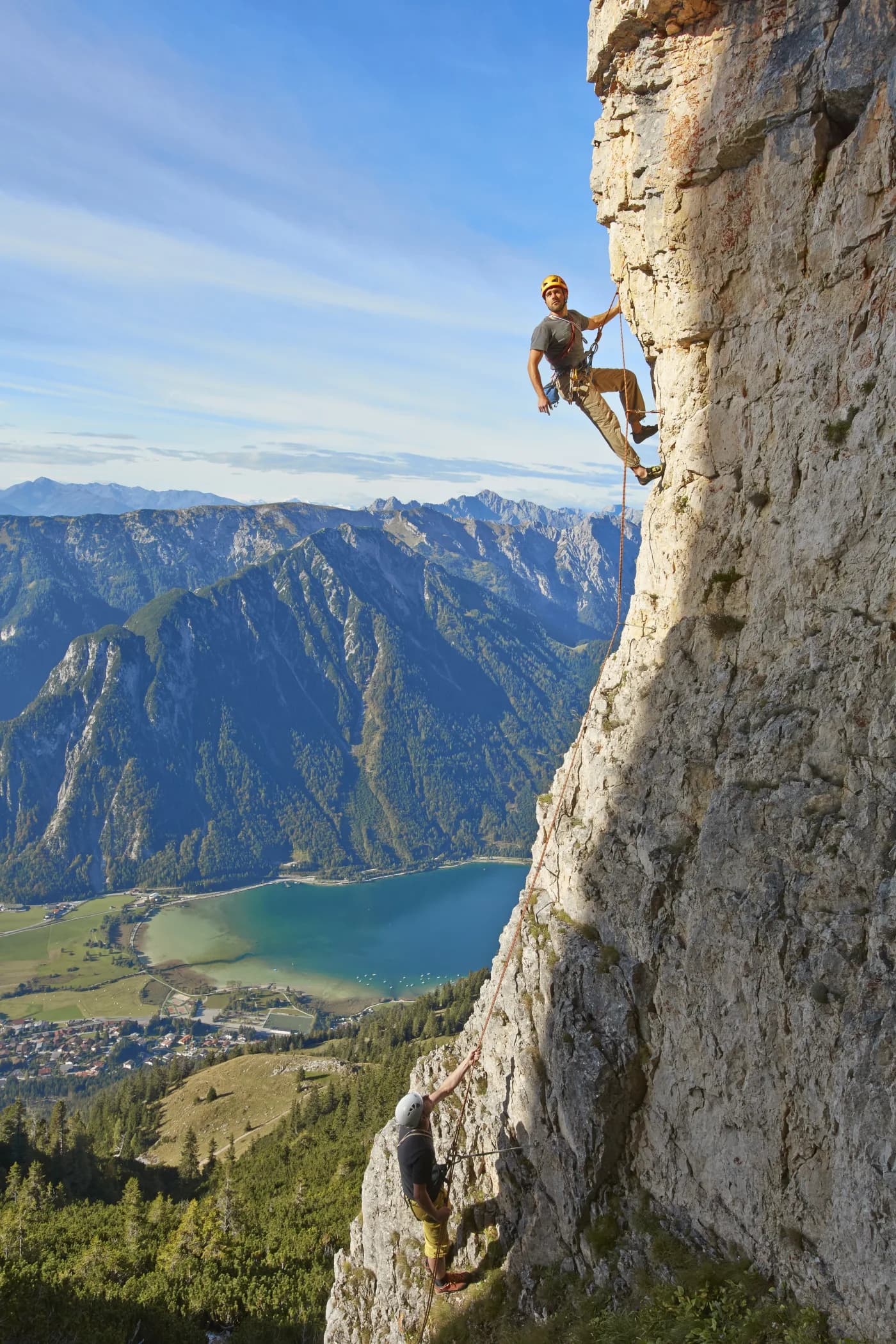 Kletterer in der Felswand im Rofangebirge, tief unten der türkisblaue Achensee