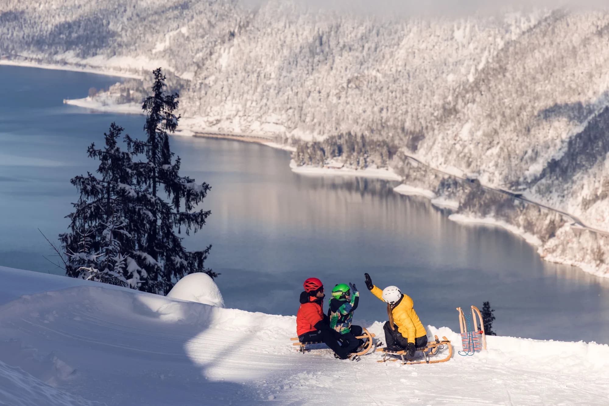 Familie rastet mit Rodeln am Zwölferkopf hoch über dem winterlichen Achensee
